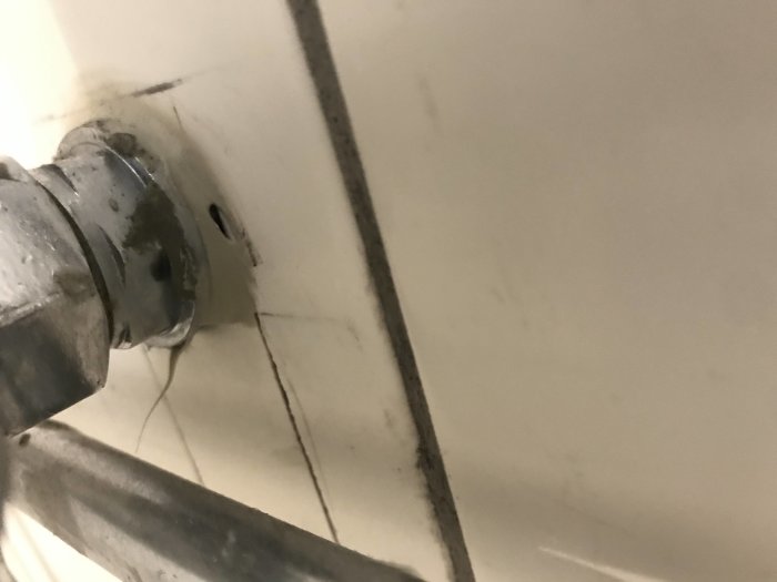 Närbild på ett vägguttag utan jordanslutning, synlig rörinstallation och slarvigt målararbete.