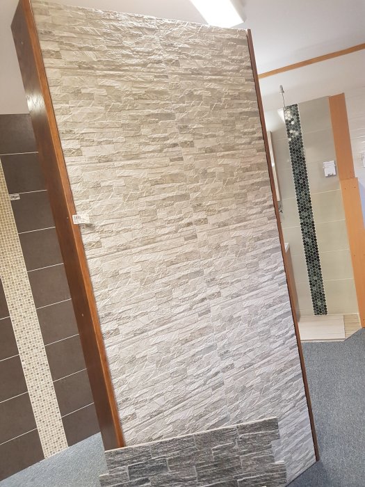 En vägg beklädd med naturstensliknande väggtegel tillsammans med synliga laminatgolv och takbelysning.