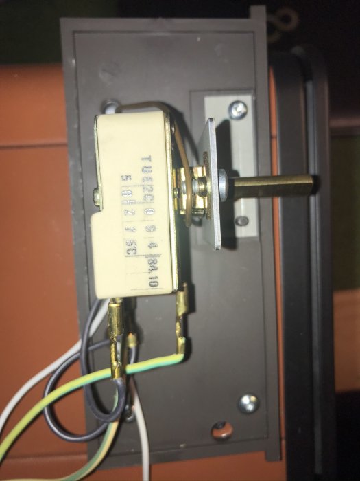Elektrisk termostat med vred och anslutningar i en bordsugn, oskarpa närbild.