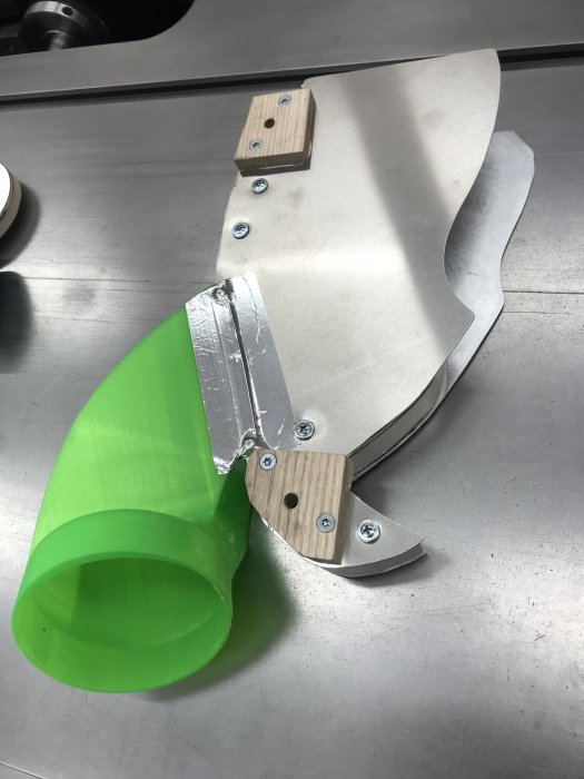 Aluminiumplåt ombyggd på bordssåg med grönt plastutblås och träfästen.