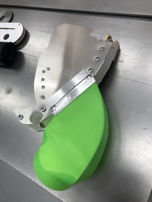 Ombyggd anordning med 1,5mm aluminiumplåt på bordssåg, förbättring för spånhantering.