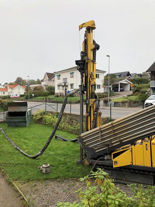 Borrigg för installation av bergvärmesystem i en trädgård framför bostadshus.