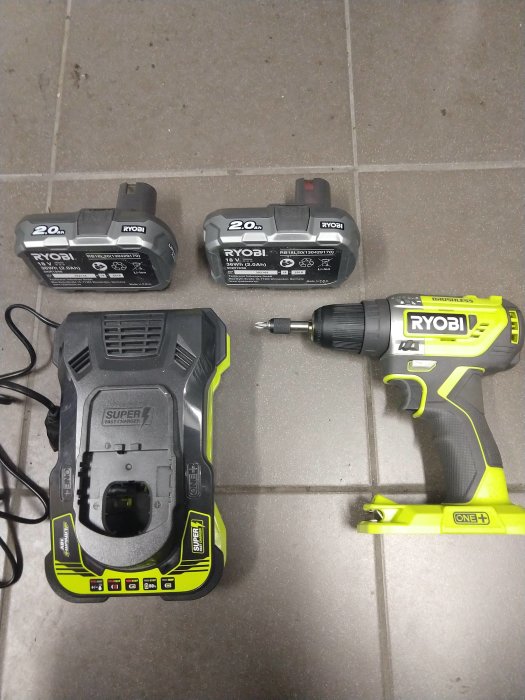 Ny Ryobi borrskruvdragare R18dd5 med två batterier och laddare på ett golv.