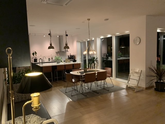 Välbelyst modernt kök och matplats med köksö, infälld belysning, matbord och stolar, inredningsdetaljer.