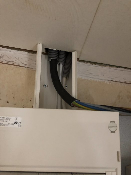 Tjock svart N1XV-kabel och flexibla rör genom skarvbox ovanför gammal undercentral.