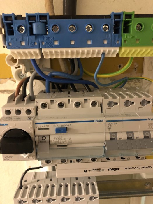 Elcentral med ena änden av kablar inkopplade, märkta med Neozed-säkringar och automatsäkringar.
