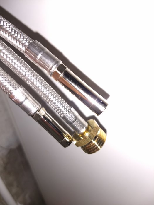 Närbild på en blandarkoppling med en 10mm slätända och vattenledningsslangar.