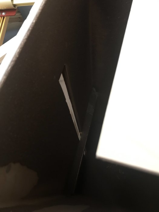 Svårseende svart fjärrkontroll blandat med mörkt spån i en hörnbinge.