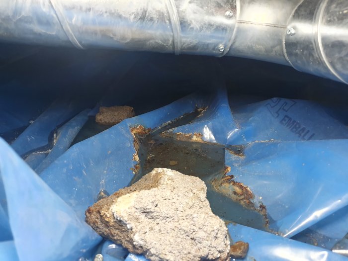 Vattenpölar och fukt på blå plastfolie i krypgrund med synliga avfuktarrör.