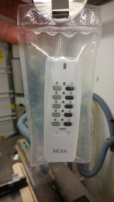 Fjärrkontroll innesluten i en dammtät vakuumpåse med stängningsmekanism och jojosnöre.