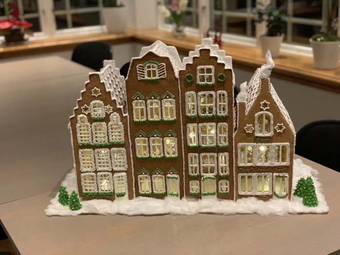Handgjorda pepparkakshus som representerar ett julpyntat kvarter på ett bord.