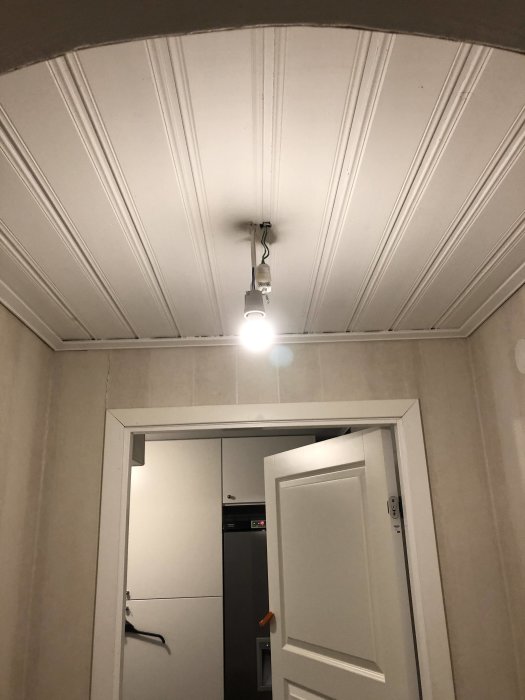 Nyinstallerad lampa på taket i hallen ovanför en dörröppning, belyser rummet starkt.