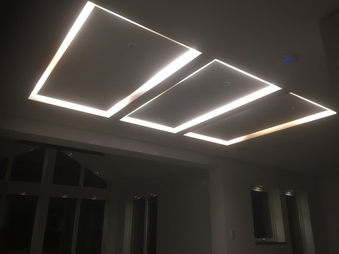 Moderna nedhängda taklampor med LED-belysning på ett mörkt tak i ett rum med fönster.