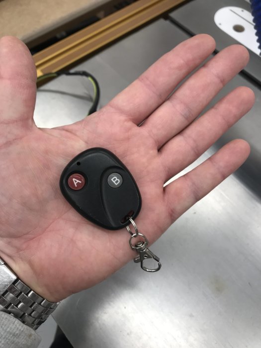 Nyckel med två knappar märkta A och B hålles i en hand, återfunnen efter fastnat i rör.