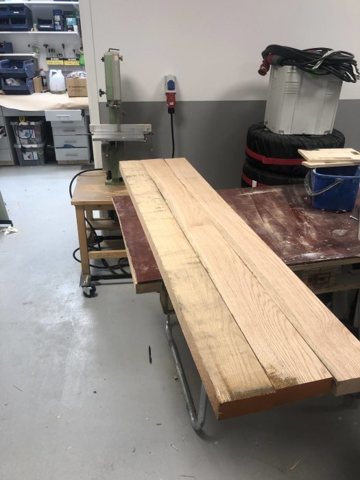 Hyvlade ekbordsskivor på arbetsbänk i verkstad, förarbeten till nattduksbord.