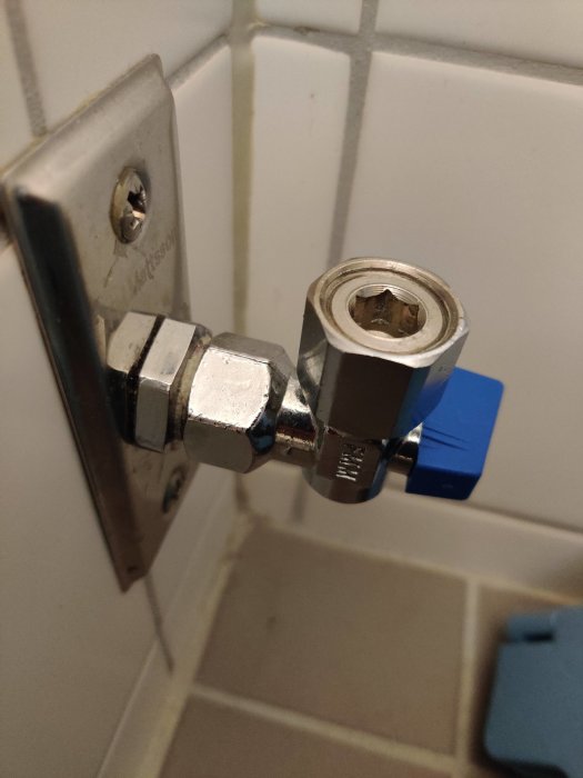 Kulventil med blå spak monterad på vit kakelvägg, fråga om dess inre komponenter.