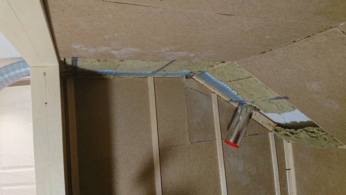 Ventilationsrör placerat i hörn under ett snedtak i ett pågående byggprojekt.
