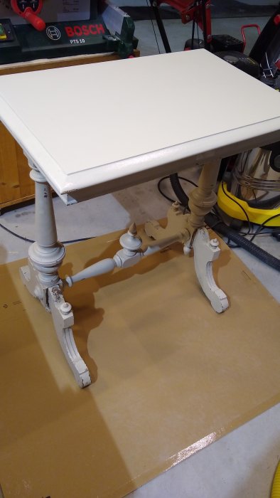 Renoverat, äldre bord målat i grå nyans, ovanpå skyddspapp.