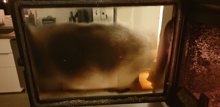 Närbild på en smutsig ugnslucka med tydligt synlig bränning och fettfläckar.
