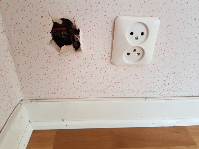 Gamla eluttag och en öppen dosa i vägg med synliga kablar och installationer.