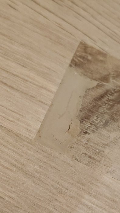 Närbild på en träbänkskiva med synlig reparation och spricka som beskrivs som en kvalitetsbrist av köparen.