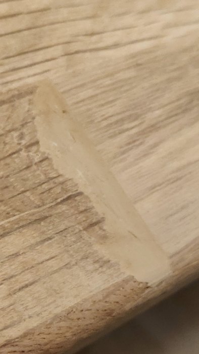 Närplan av en träbänkskiva med en synlig lagning i form av en ljusare träfyllning.