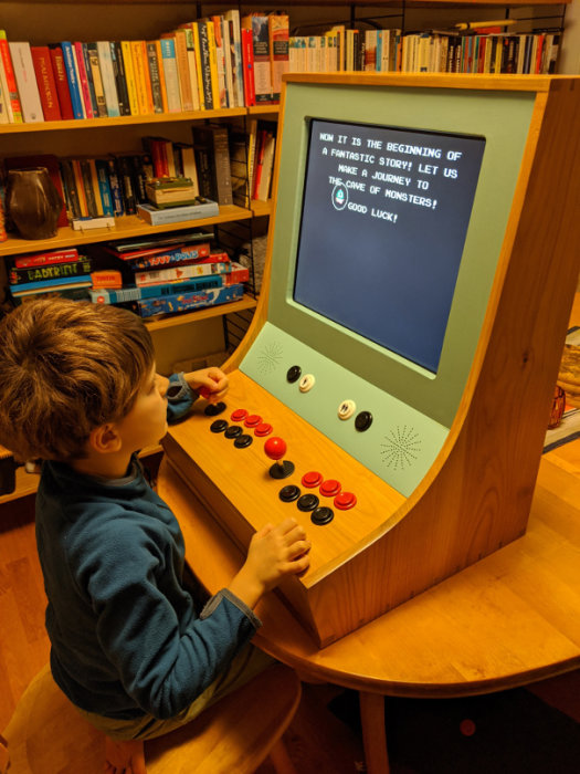 Barn spelar på en hemmagjord arkadmaskin med text på skärmen.