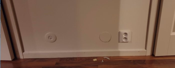 Gammaldags elinstallation med löst doslock och hopsnurrad kabel vid en väggbaseboard.