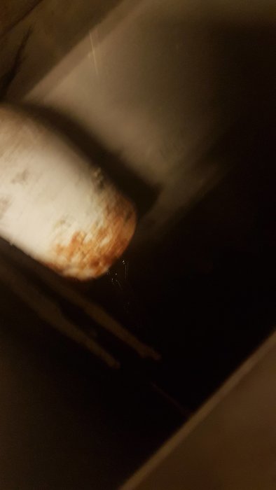 Vatten droppar från ett skvallerrör i mörker, tecken på möjlig läcka.