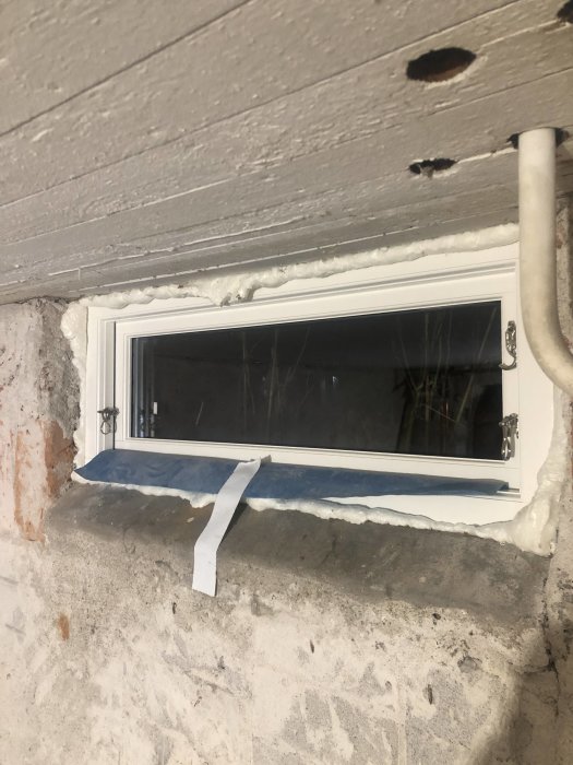 Nytt installerat fönster i en grovputsad vägg med synlig isolering och ångspärr.