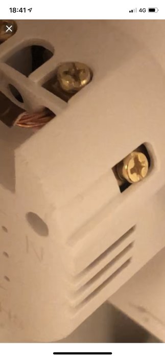 N-skruv i en strömbrytare och trådar skalade längre än rekommenderat med isolering synlig.