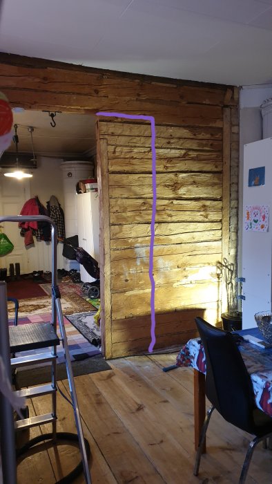 Delvis målad timmervägg i ett gammalt hus med markerad öppning som användaren funderar på att bredda.