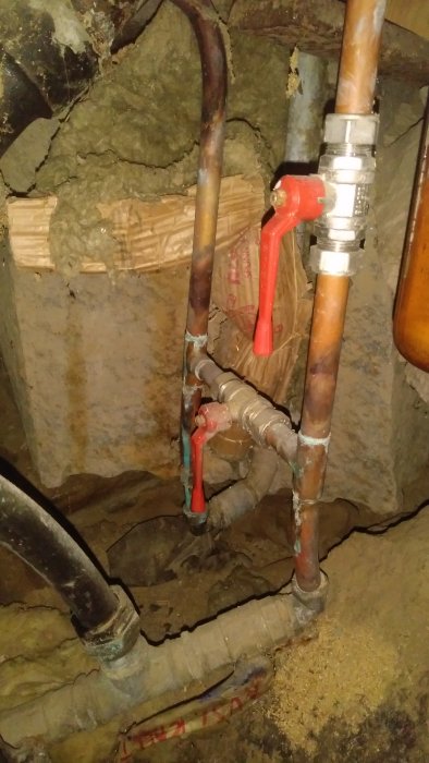 Kallvattenrör och galvaniserade rör i en grov källare med synliga isolering och ledningar.