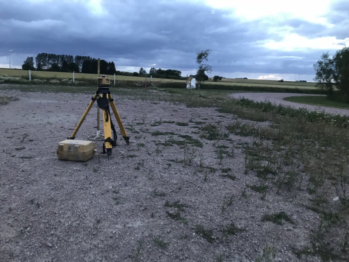 En byggplats för ridhus med mätningsinstrument i förgrunden och öppen mark i bakgrunden vid skymning.