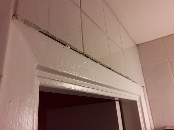 Springor mellan kakel och dörrkarm i ett badrum som behöver fogning eller tätning.