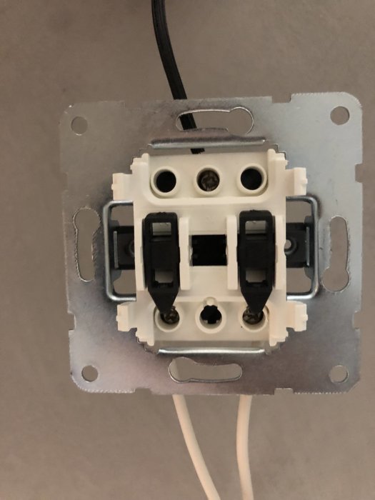 Öppen elbrytare monterad på vägg med synliga anslutningar och två svarta knappar.