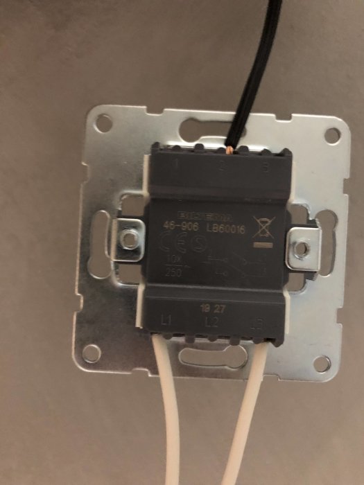 En öppen väggströmbrytare med exponerade trådar och anslutningar, inklusive märkning för dimmerfunktion.