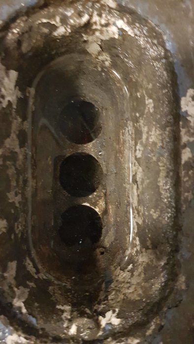 Igengrodd och smutsig golvbrunn i källare med synliga stopp och fuktavlagringar.