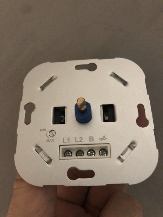 Hand håller en elektrisk dimmer med skruvanslutningar märkta L1, L2, och B, samt en MIN-MAX-switch.