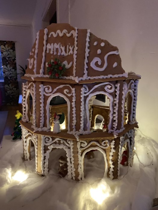 Pepparkaksmodell av Colosseum med dekorationer och små figurer föreställande tomten och renar.