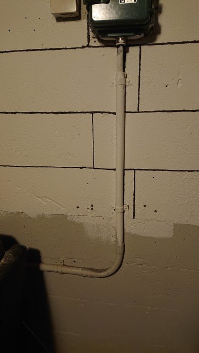 Elektrisk installationskabel i vp-rör löper längs en murad vägg till en elcentral.