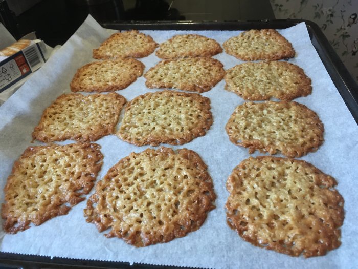 Nybakade knäckeflarn på bakplåtspapper med gyllenbrun färg och synliga hål efter gräddning.