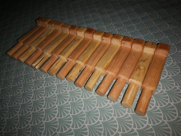 Täljda träbrädor med profilerade kanter arrangeras sida vid sida på ett mönstrat underlag, linoljelasyr på engelsk röd nämns.