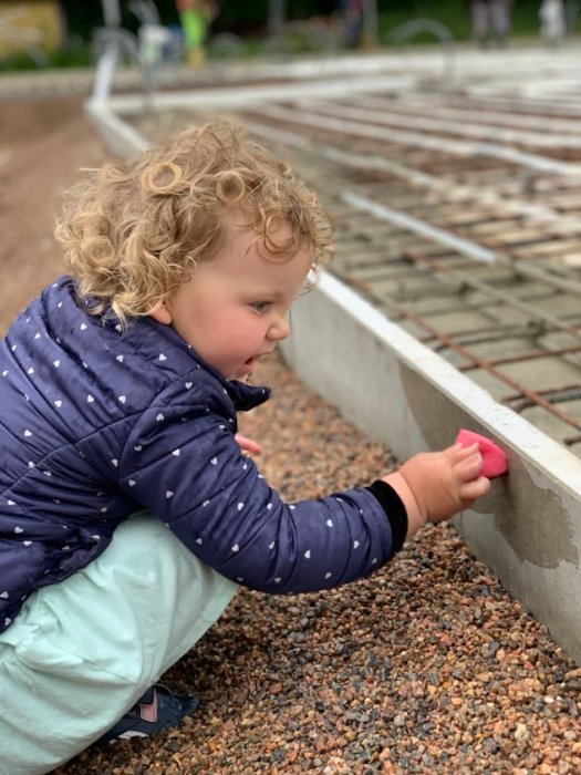 Barn hjälper till på byggarbetsplats med gjutet mellanbjälklag och trplåttak under uppförande.