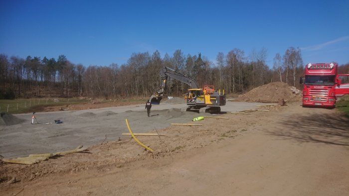 Paddockområde under konstruktion med grävmaskin, lastbil och högar av grus och jord.