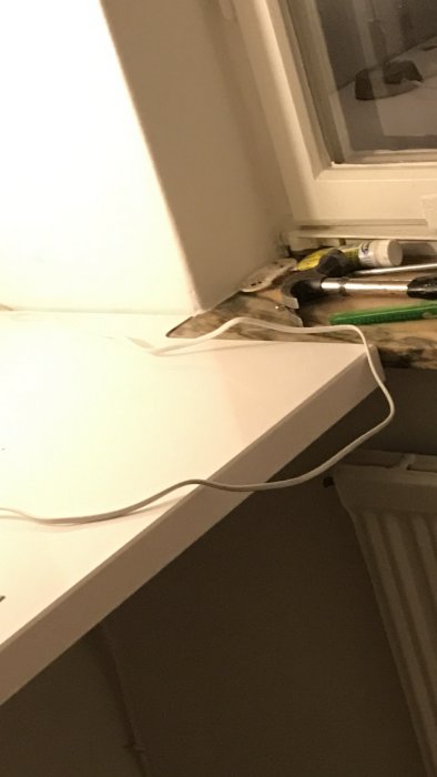 Fönsterbräda i behov av renovering med verktyg och byggmaterial på golvet.