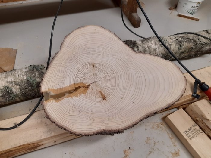 Hyvlad och behandlad björkträskiva med synliga årsringar, epoxifylld spricka, bredvid verktyg och OSMO hårdvaxolja.
