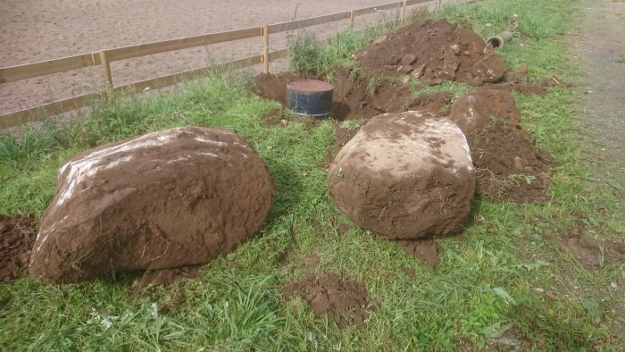 Två stora stenbumlingar i gräsmark nära paddock under byggnation.