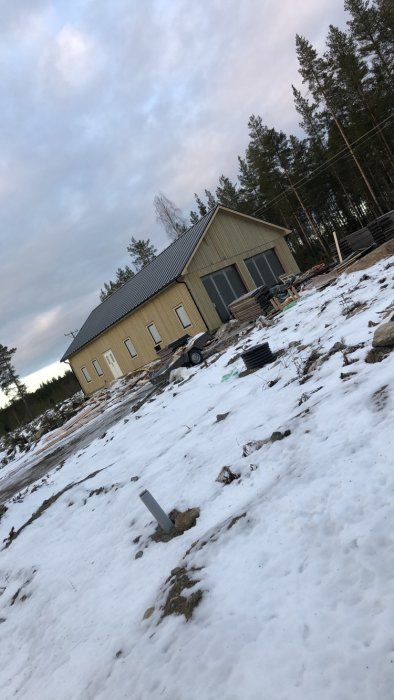 Byggnad med två garageportar och vit dörr på snötäckt mark.