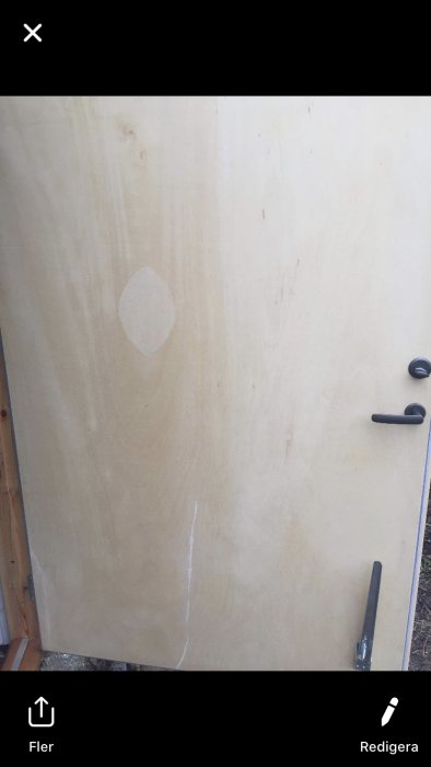 Garagedörr med synlig limning och repor, ej oljad eller laseras, med handtag och lås.